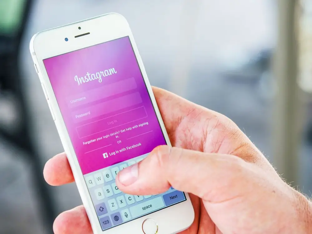 Person logging into Instagram on phone — monitoring engagement and comments for Reels growth in 2026