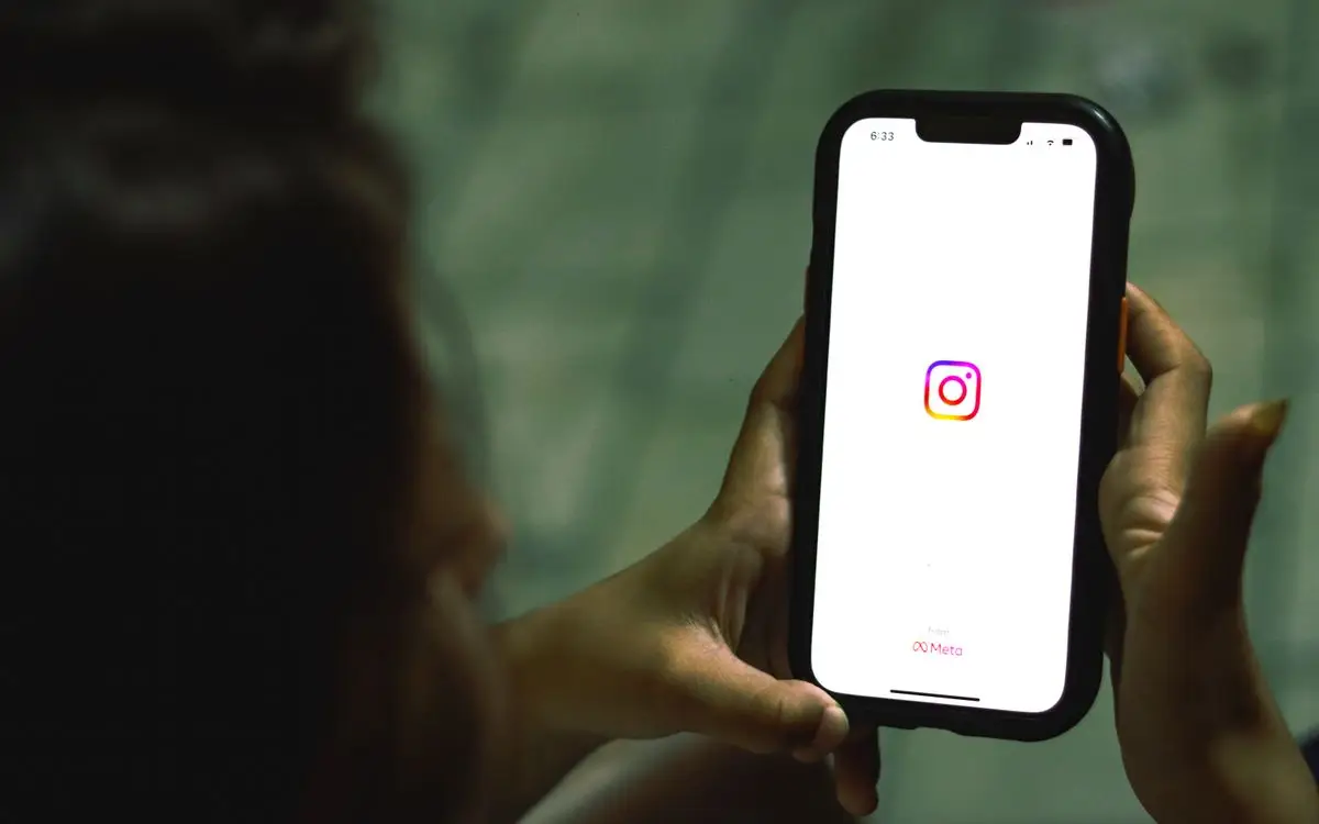 Hand holding smartphone showing Instagram app — Instagram Reels reach strategy in 2026