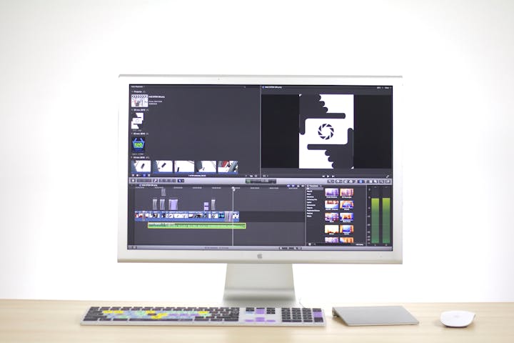 Clean workspace with iMac displaying professional video editing software interface